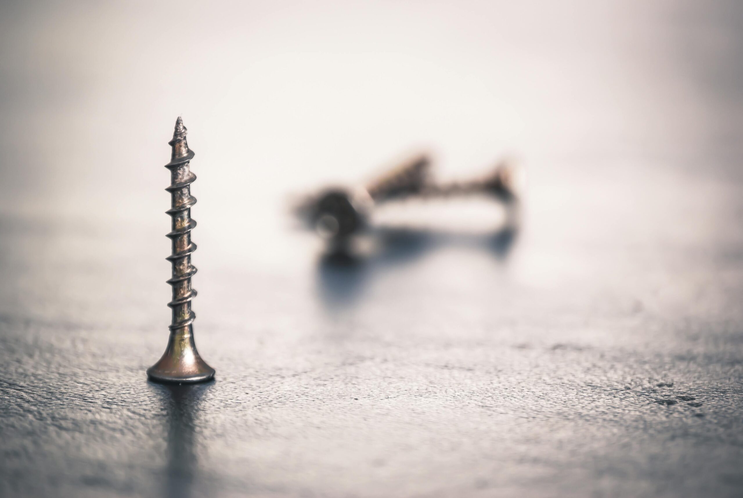 High-detail close-up of sharp metal screws on a textured surface with soft focus.